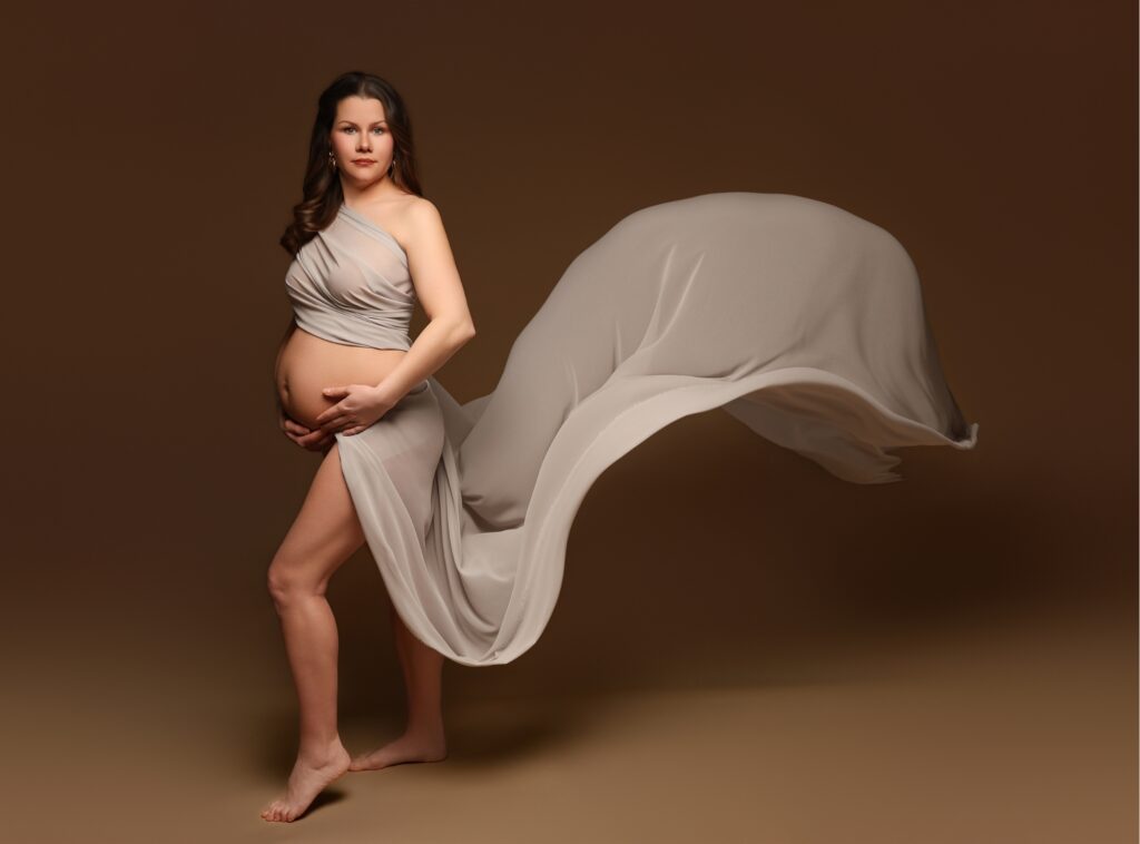 Gravid kvinna poserar i studio mot beige bakgrund