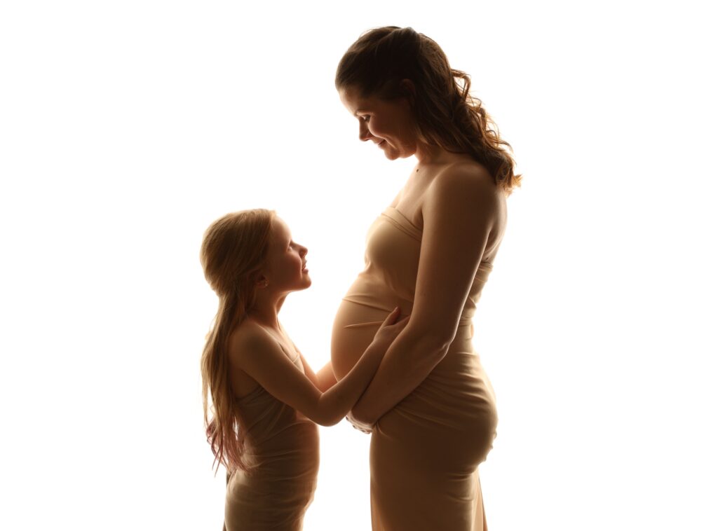 Silhuett av gravid kvinna och barn mot vit bakgrund