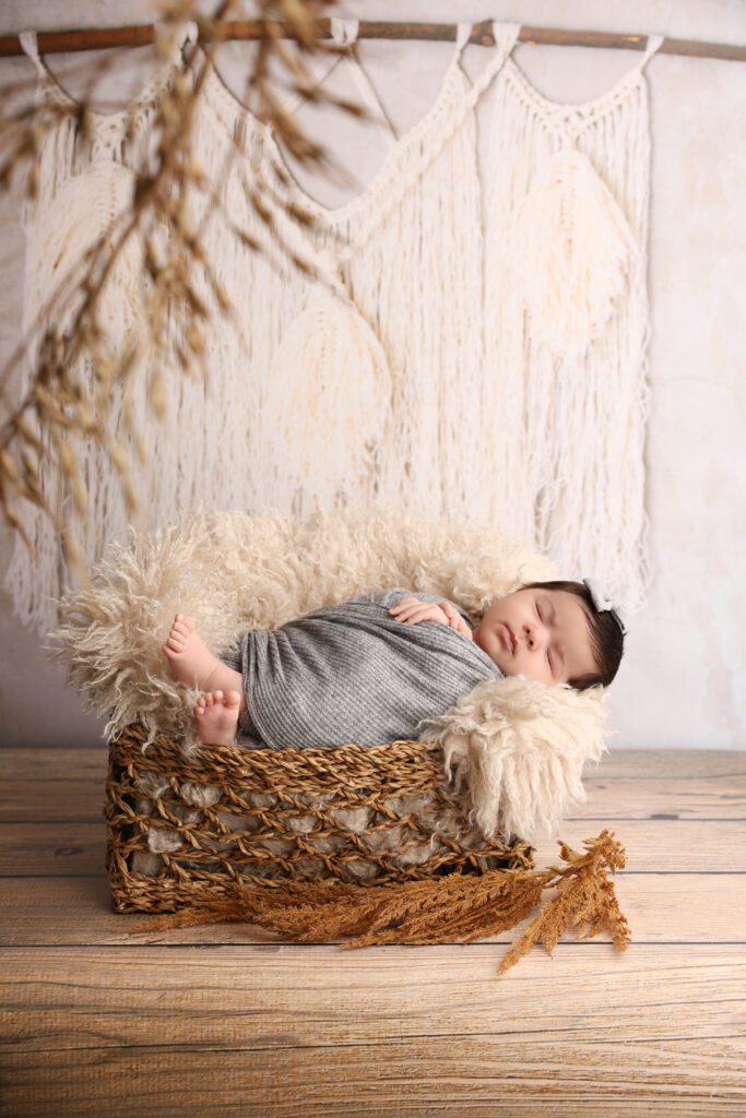 Sovande nyfödd bebis i korg med mjuk filt