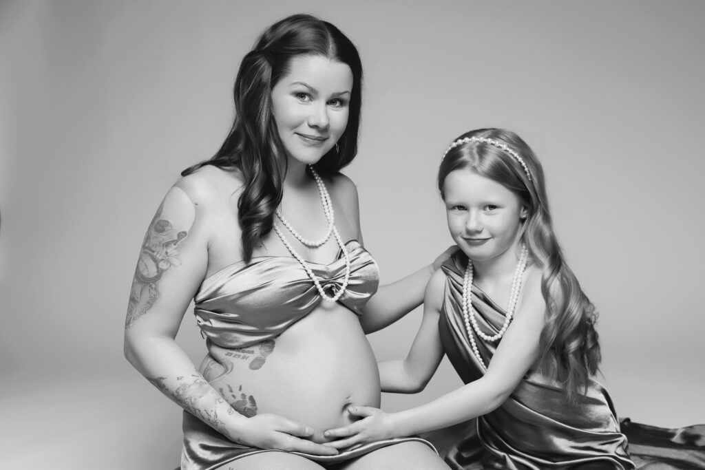 Gravid kvinna poserar med barn i studio