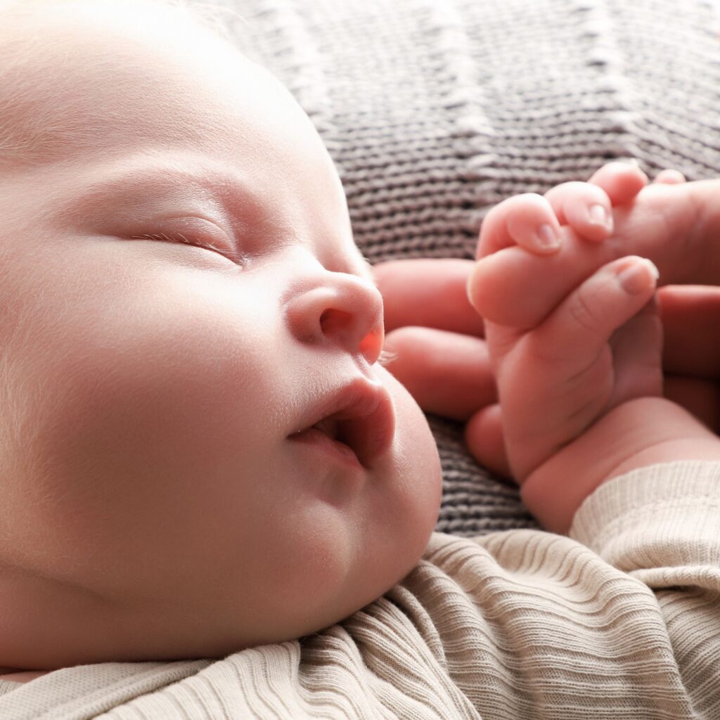 Nyfödd bebis som håller förälders finger