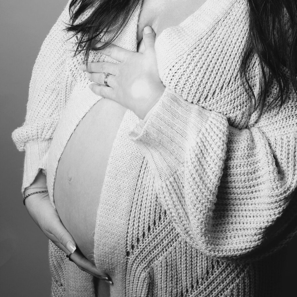 Gravid kvinna håller händerna över magen