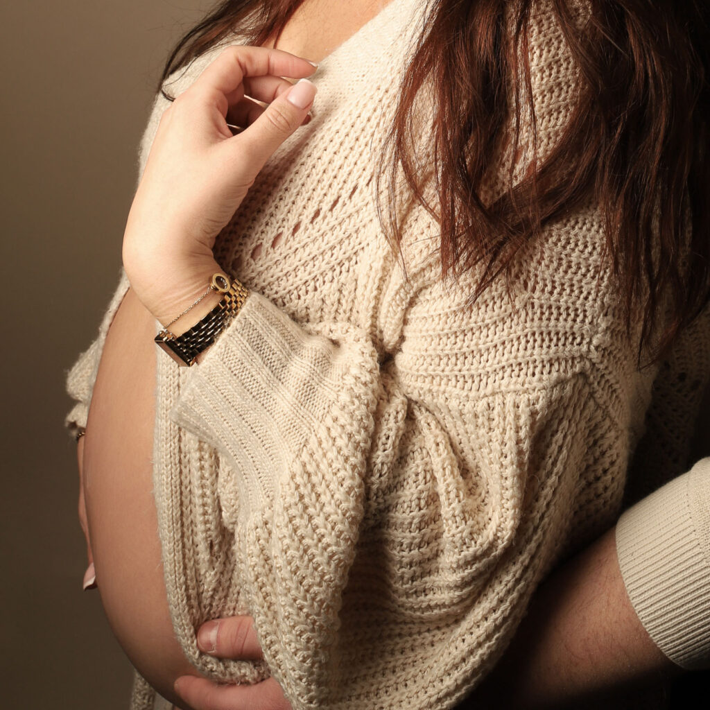 Närbild på gravid mage i stickad tröja