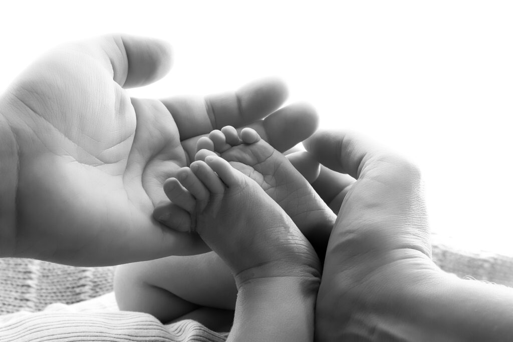 Föräldrars händer som håller om nyfödd bebis fötter